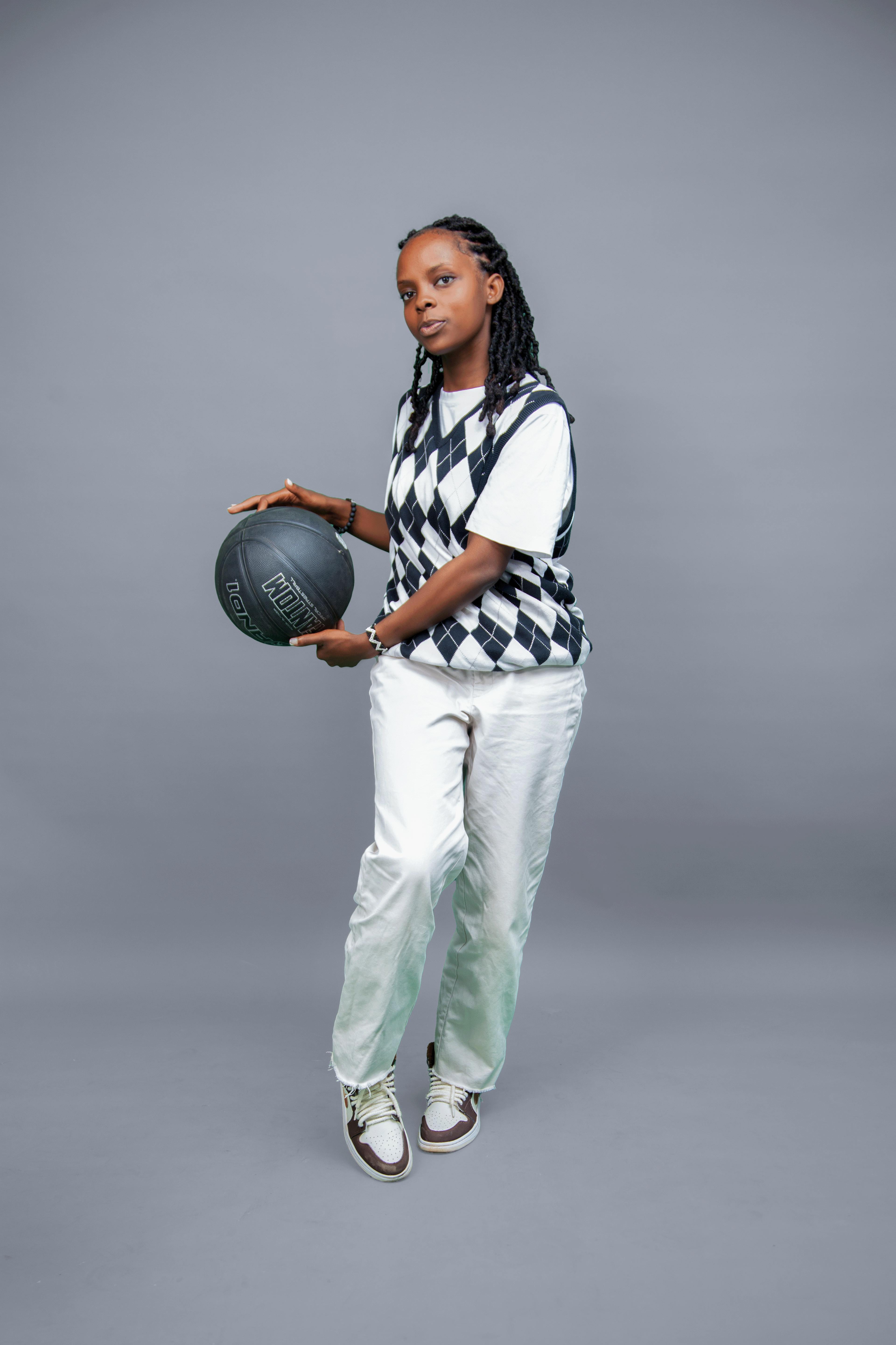 a woman in a vest and pants holding a basketball