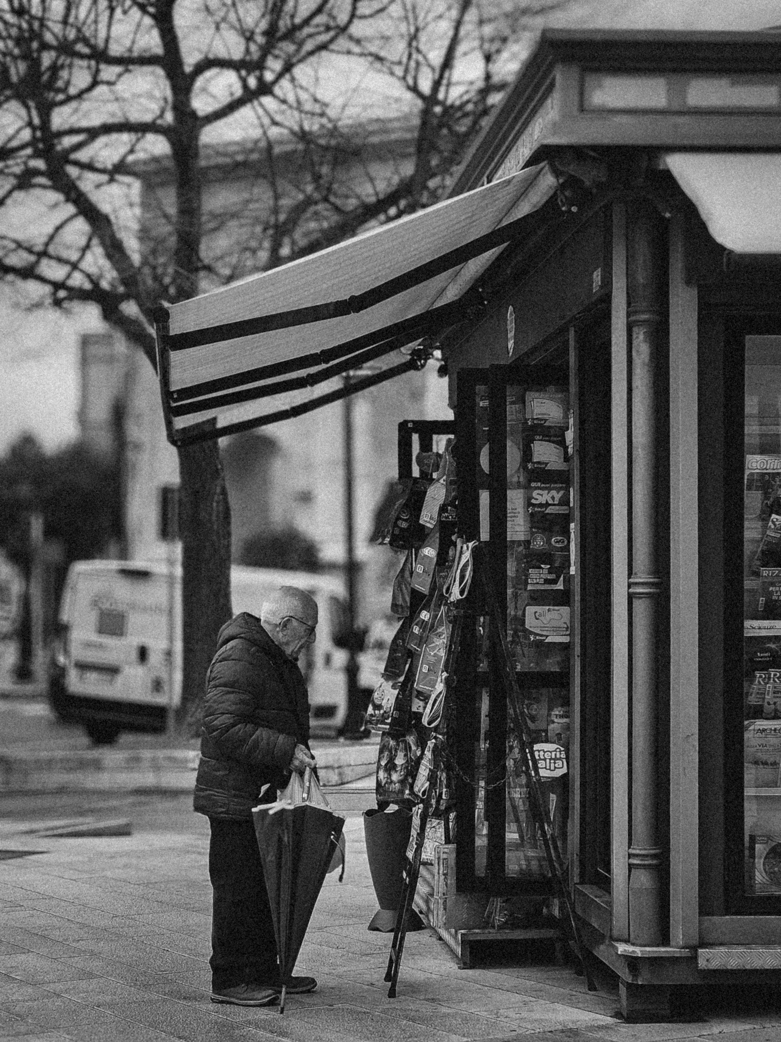 A man is standing outside of a store with an umbrella · Free Stock Photo