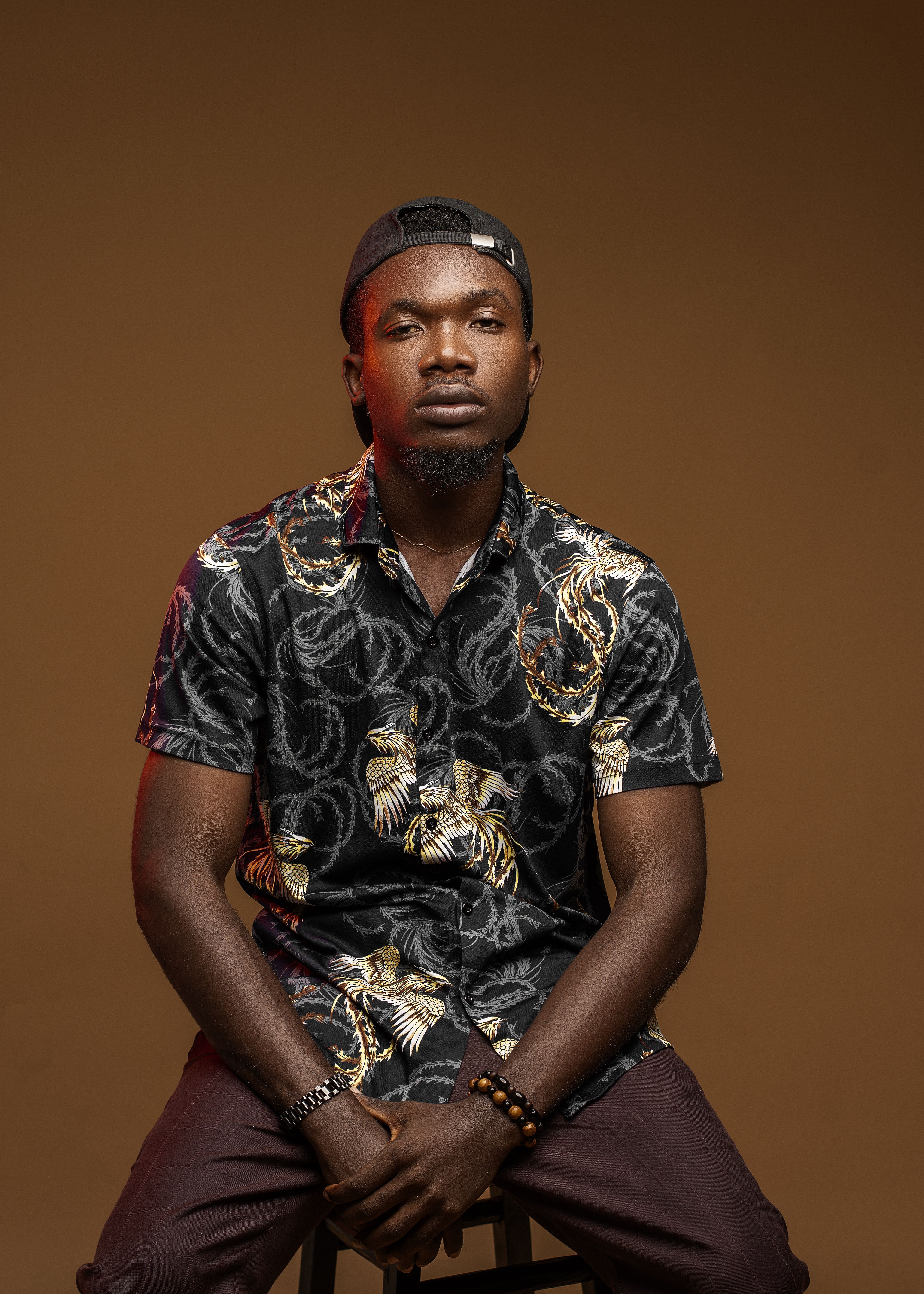 Confident young man in fashionable black shirt poses for a portrait in a studio setting.