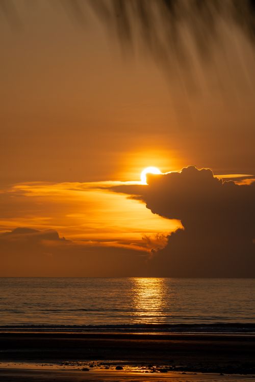 Free Captivating sunset with silhouetted clouds reflecting over a tranquil ocean. Perfect for serenity and travel themes. Stock Photo