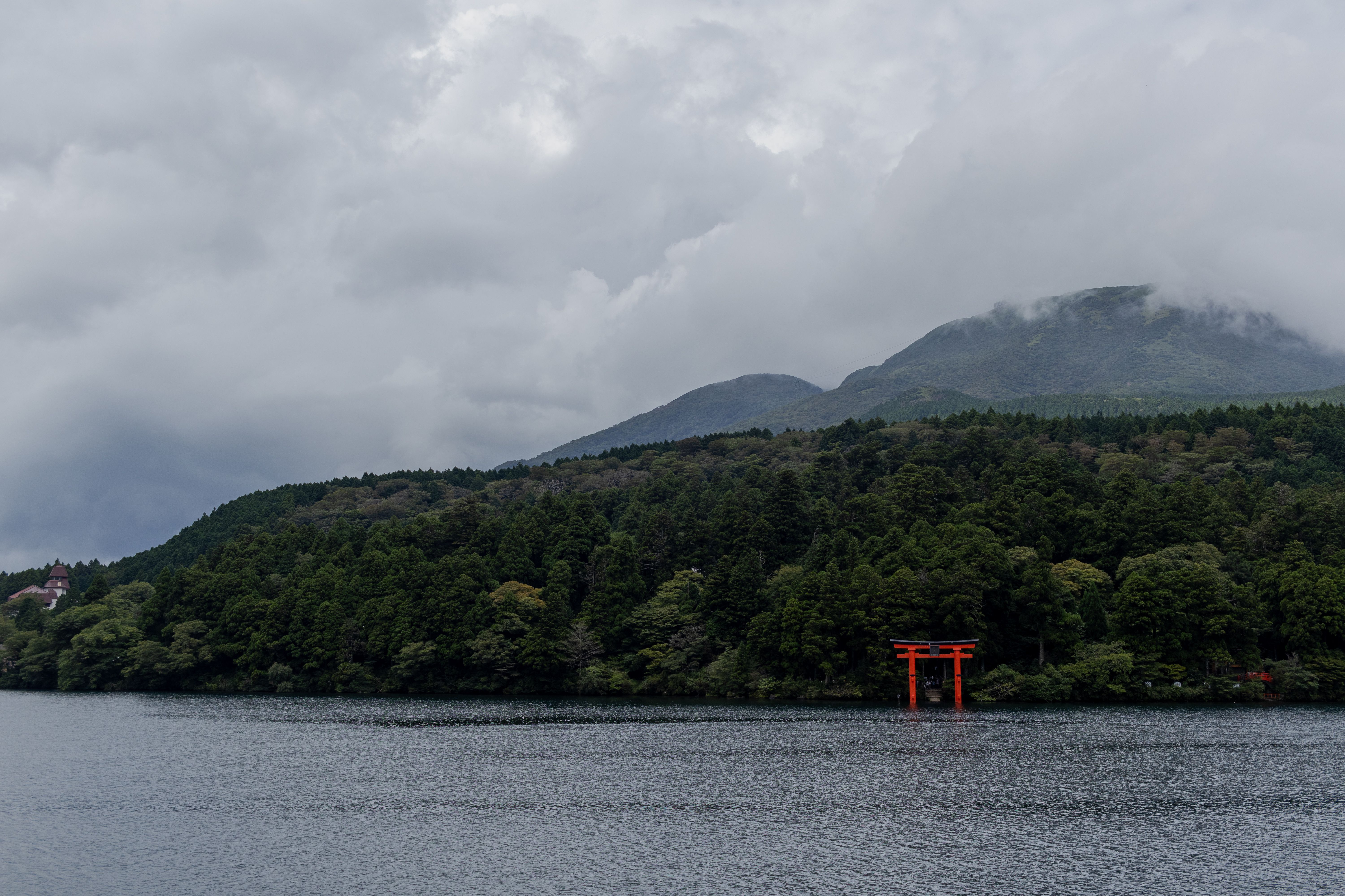 A red tori gate sits on a lake with mountains in the background · Free ...