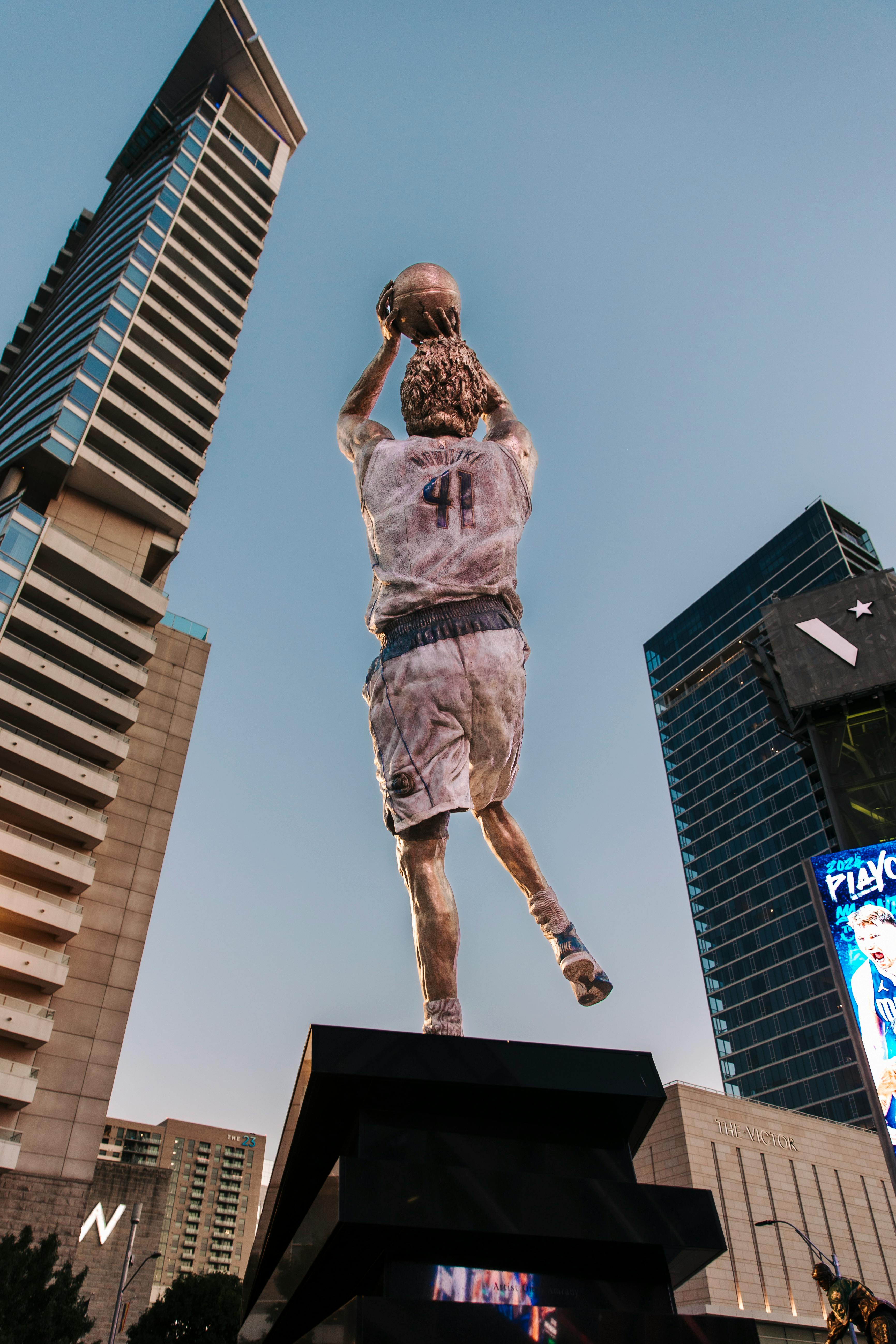 a statue of a basketball player in front of tall buildings