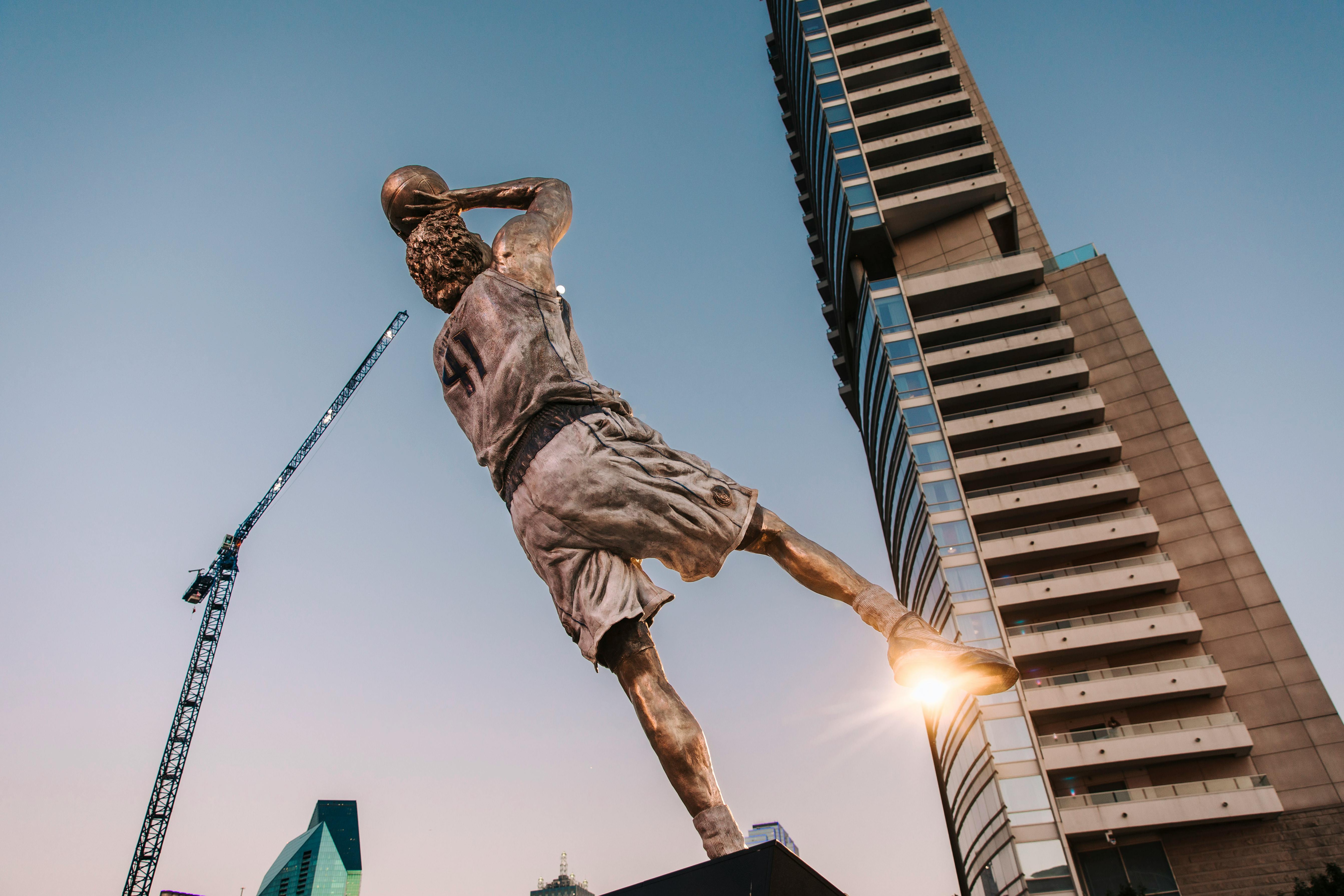 a statue of a basketball player in front of tall buildings