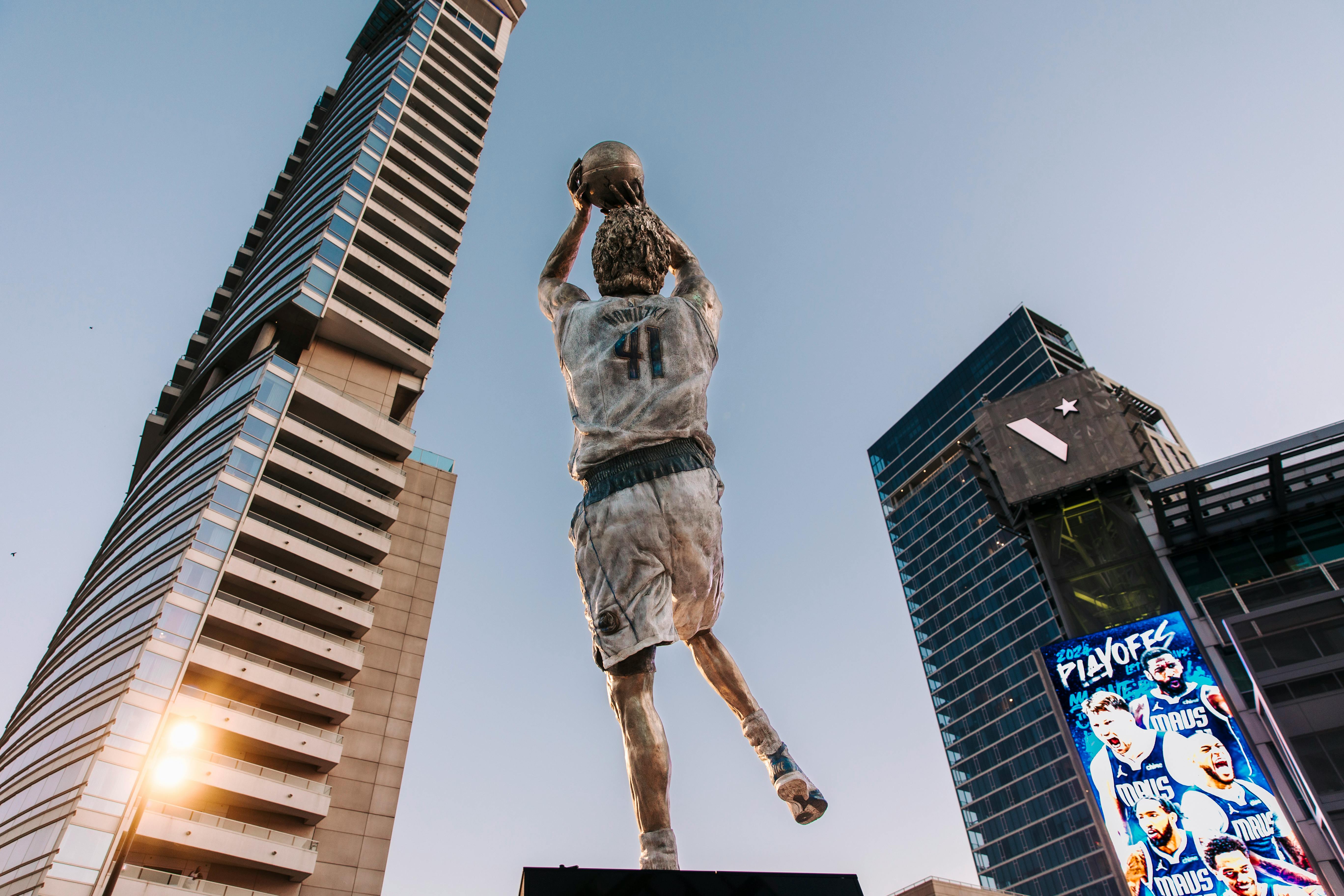 a statue of a basketball player in front of tall buildings