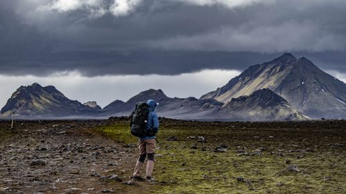 Free Person hiking with backpack in dramatic Icelandic mountains under cloudy skies. Stock Photo