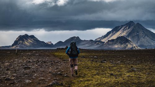 Free A lone hiker traverses a rugged trail amidst the dramatic Icelandic mountains. Stock Photo