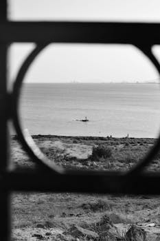 Artistic black and white seashore view with circular frame, capturing serene ocean landscape.