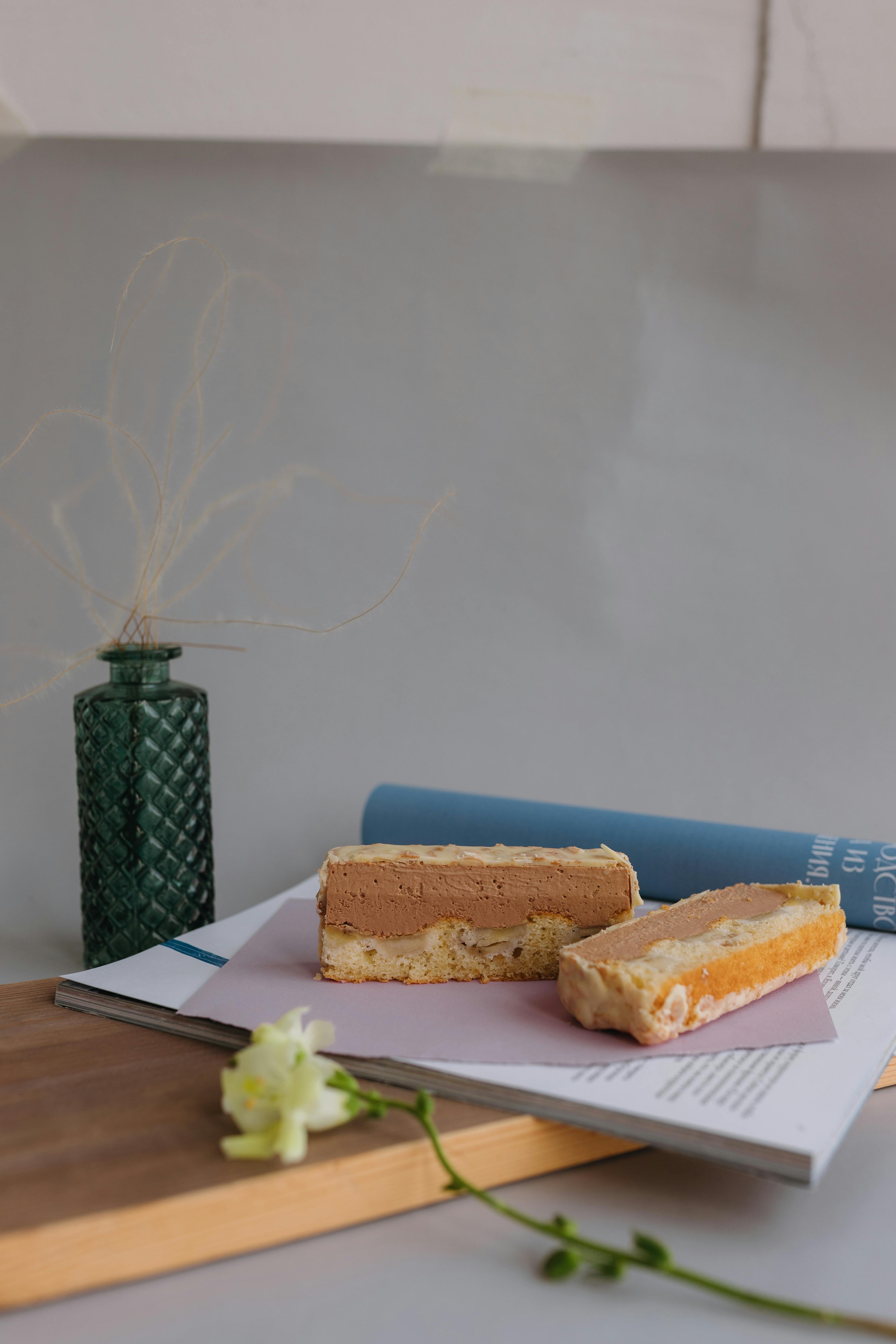 a slice of cake sitting on a cutting board next to a vase