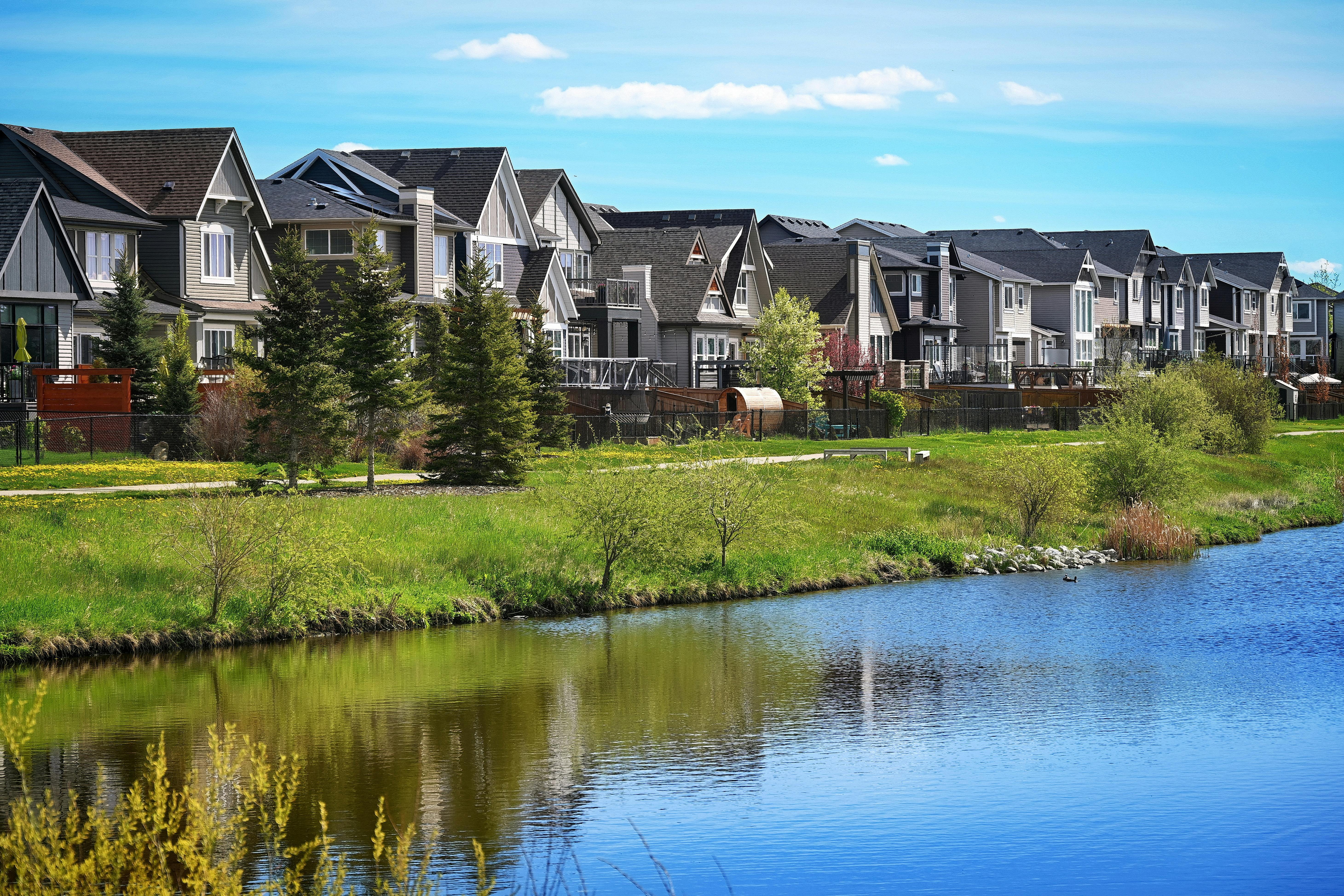 Modern suburban houses lining a serene pond in Airdrie, Alberta, Canada.