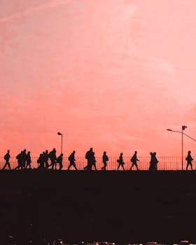 日落时分，人们走过一座桥，在温暖的天空下勾勒出戏剧性的轮廓