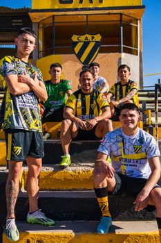 Young soccer players in colorful uniforms pose proudly on stadium steps.