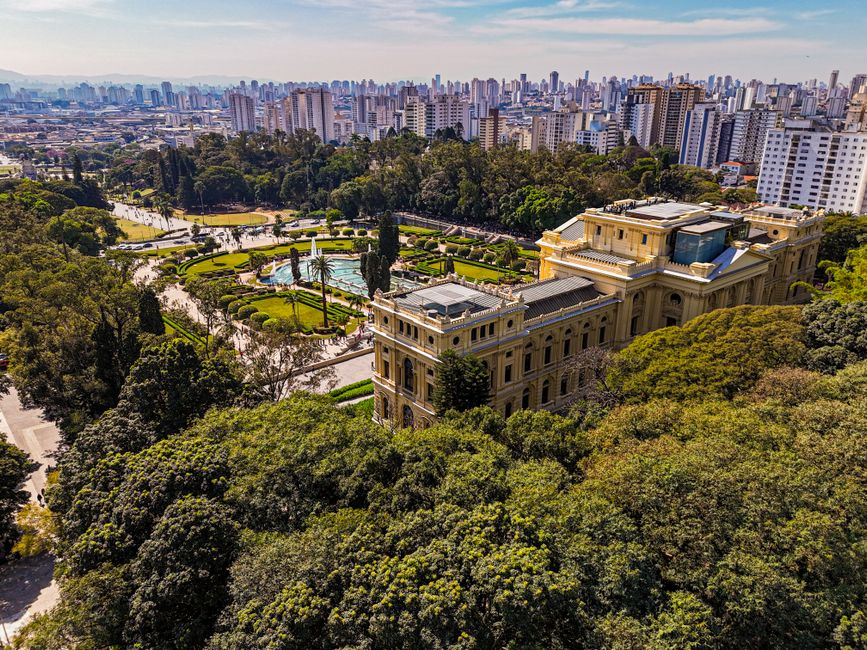 Stunning aerial photograph of Ipiranga Museum amidst lush gardens and São Paulo skyline.