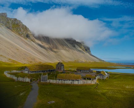 Aerial view of a Viking settlement in Iceland surrounded by mountains and a tranquil lake.