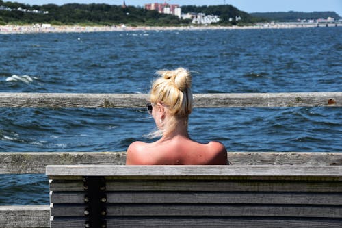 Free Woman Sitting on Grey Bench in Front of Body of Water Stock Photo