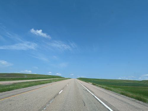 Free A straight highway disappearing into the horizon under a clear blue sky. Stock Photo