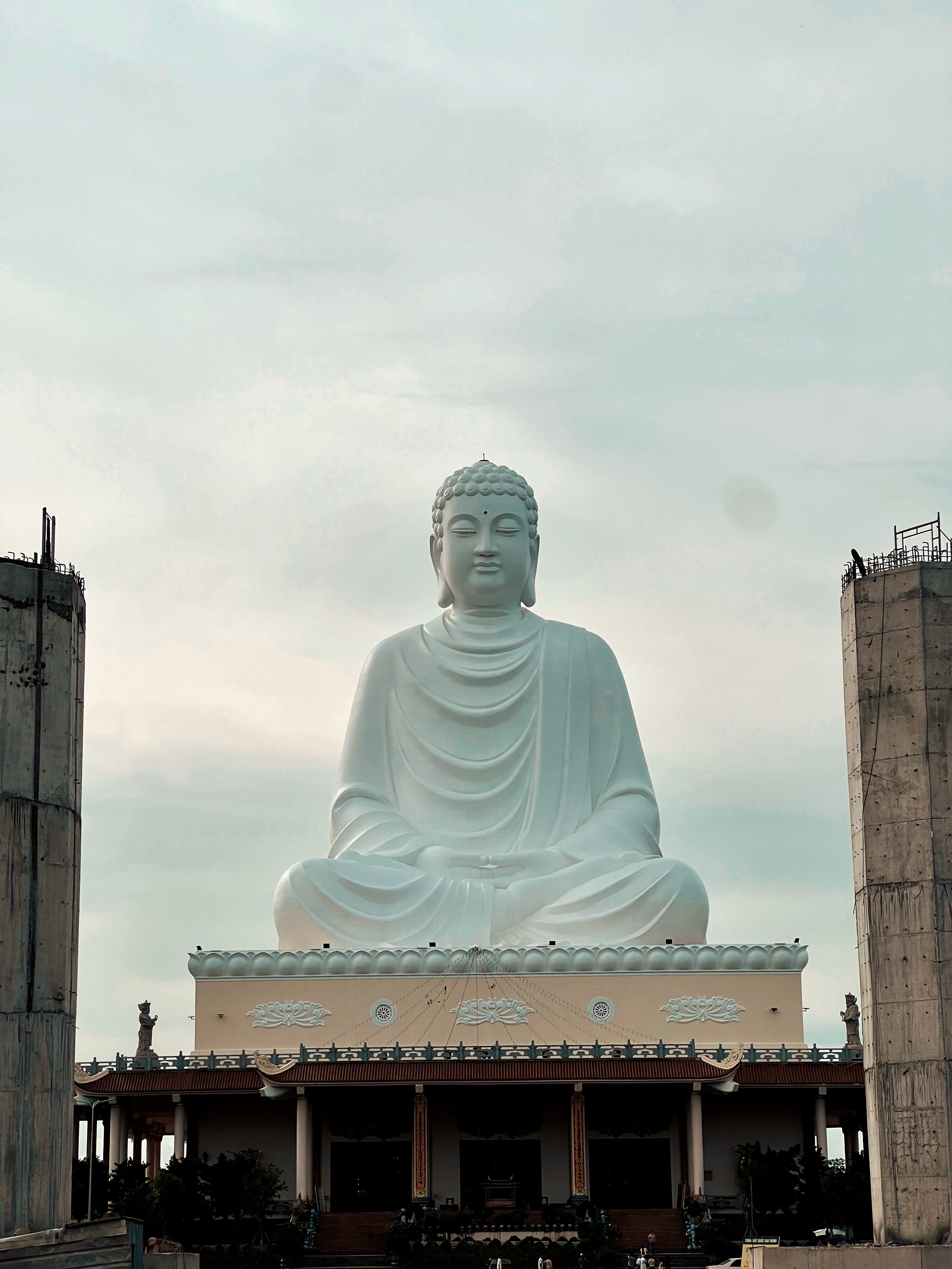 A large buddha statue sitting in front of a building · Free Stock Photo