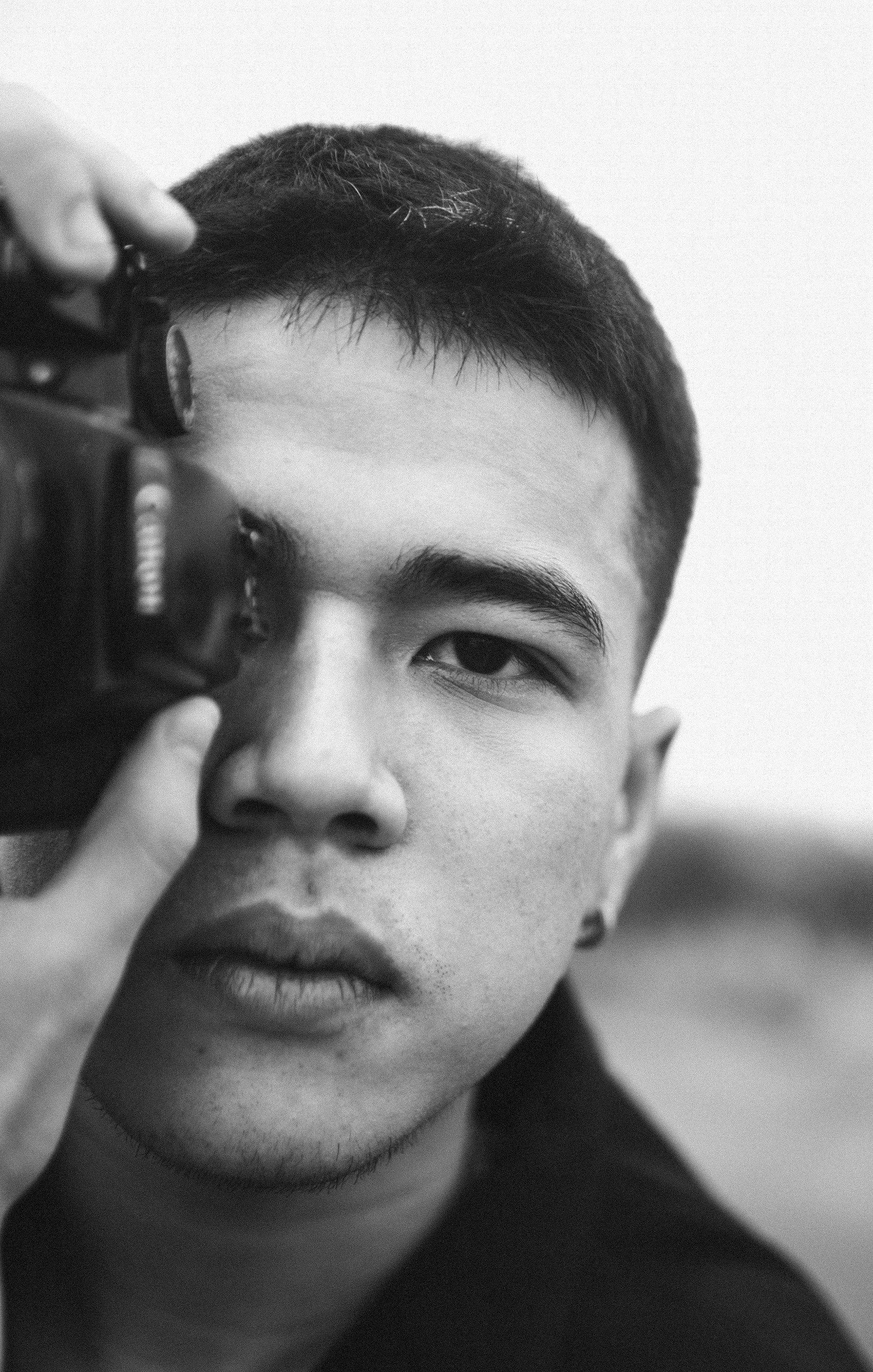 Black and white close-up portrait of a photographer holding a camera.