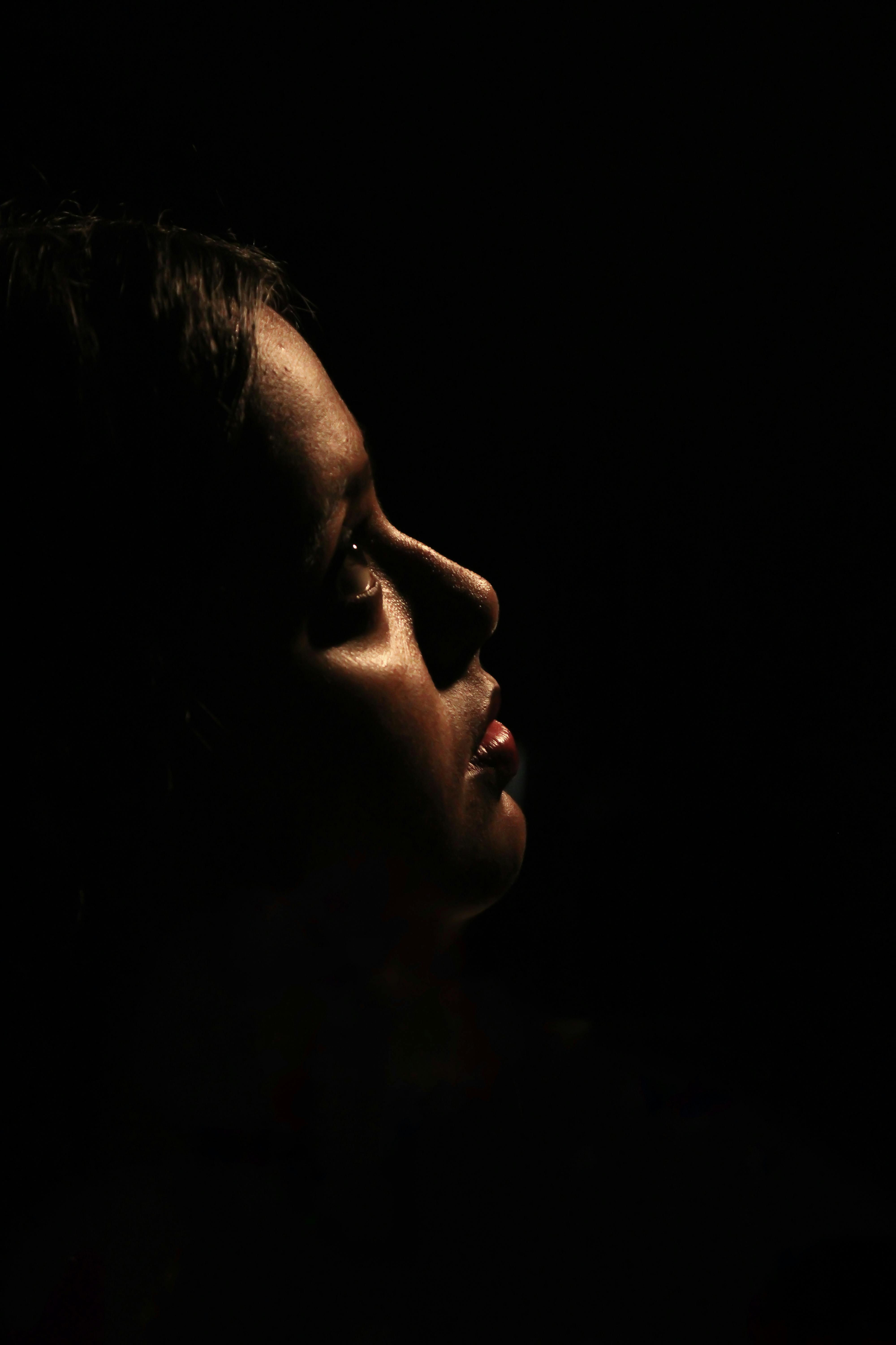 A striking side profile portrait with dramatic shadow play and focused lighting.