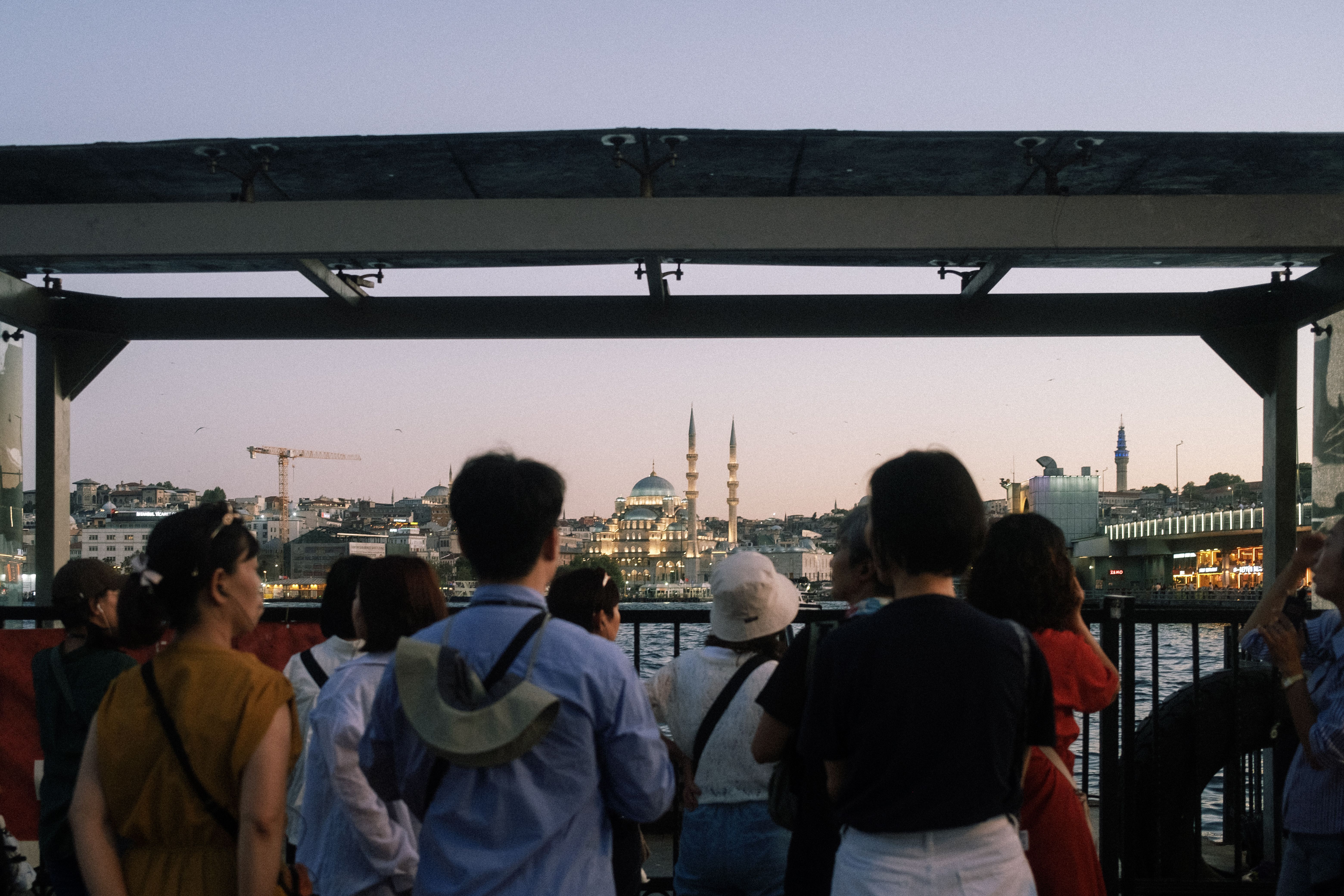 A group of tourists gathered at dusk, capturing Istanbul's skyline with mosques and cityscape.