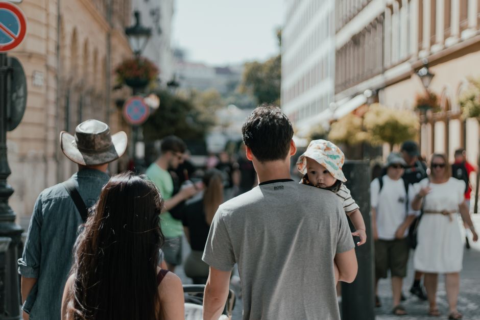 Una familia camina por una calle urbana concurrida flanqueada por edificios históricos.