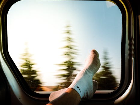 Feet in socks resting by car window with blurred trees, capturing a tranquil travel moment.