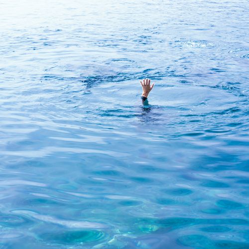 Free A lone hand reaches out from the turquoise ocean, creating a sense of intrigue and drama. Stock Photo
