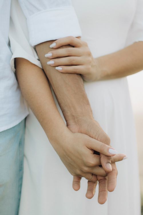 Free A close-up of a couple tenderly holding hands, symbolizing love and unity. Stock Photo