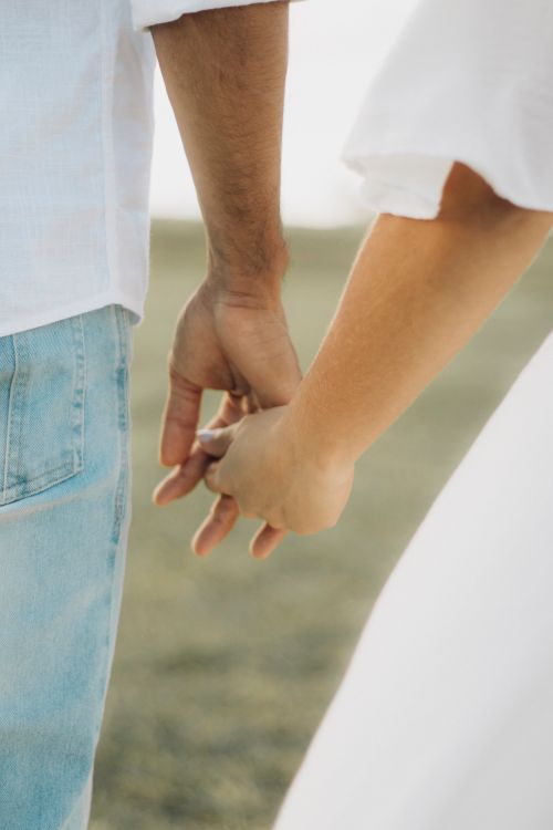 Free Close-up of a couple holding hands, symbolizing love and connection during a summer day. Stock Photo