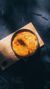 Brightly lit omelette in a pan resting on a wooden cutting board, perfect for breakfast inspiration.