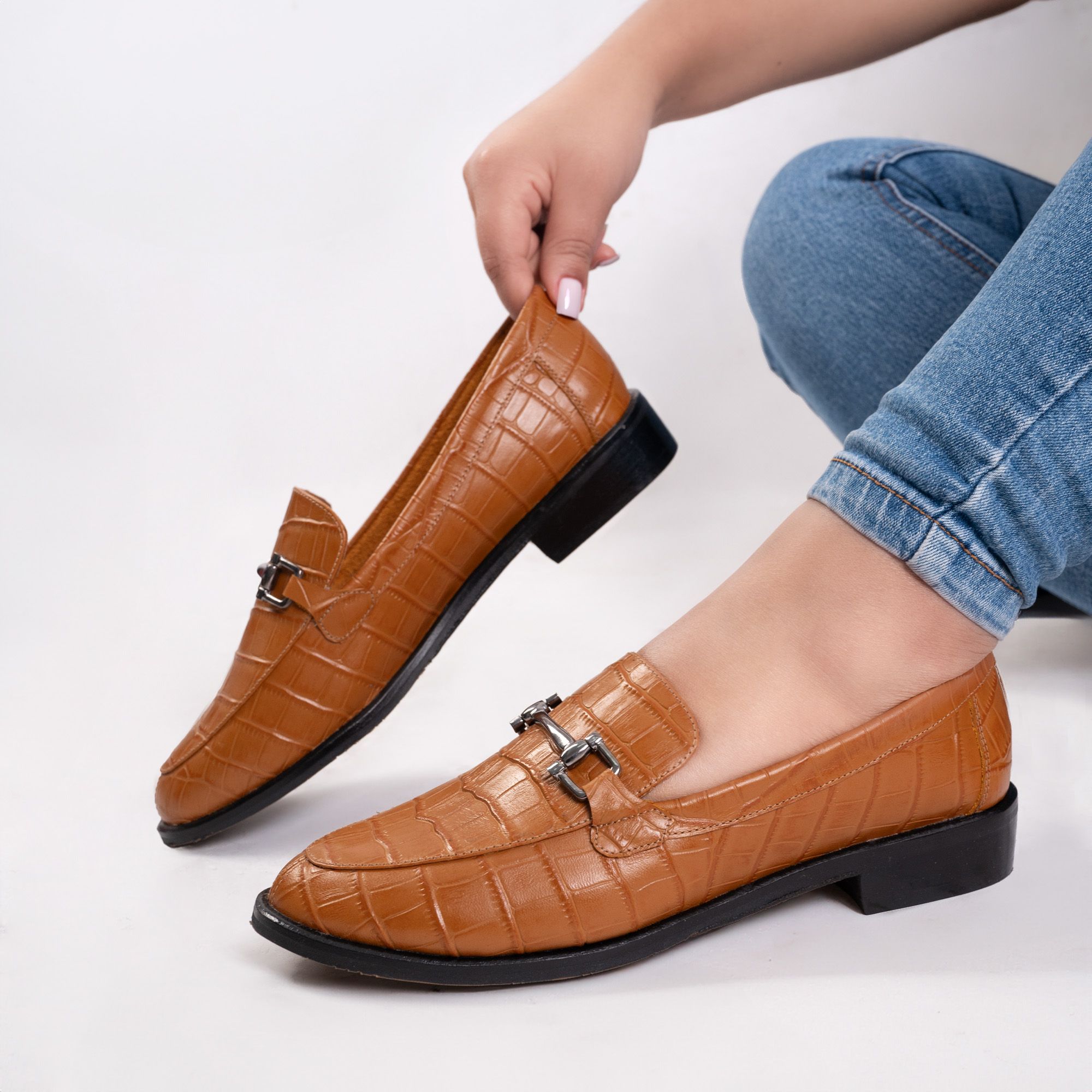 Tan croc-embossed leather loafers held against a white backdrop — photo by José Martin Segura Benites on Pexels