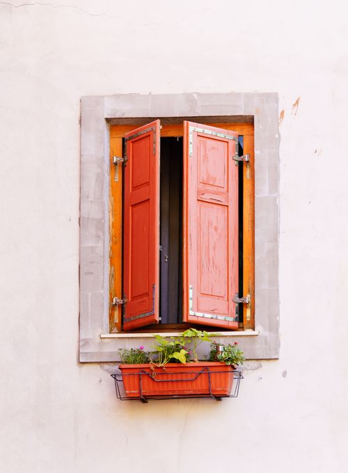 Free Charming rustic window with red wooden shutters and a flower box on a vintage building facade. Stock Photo