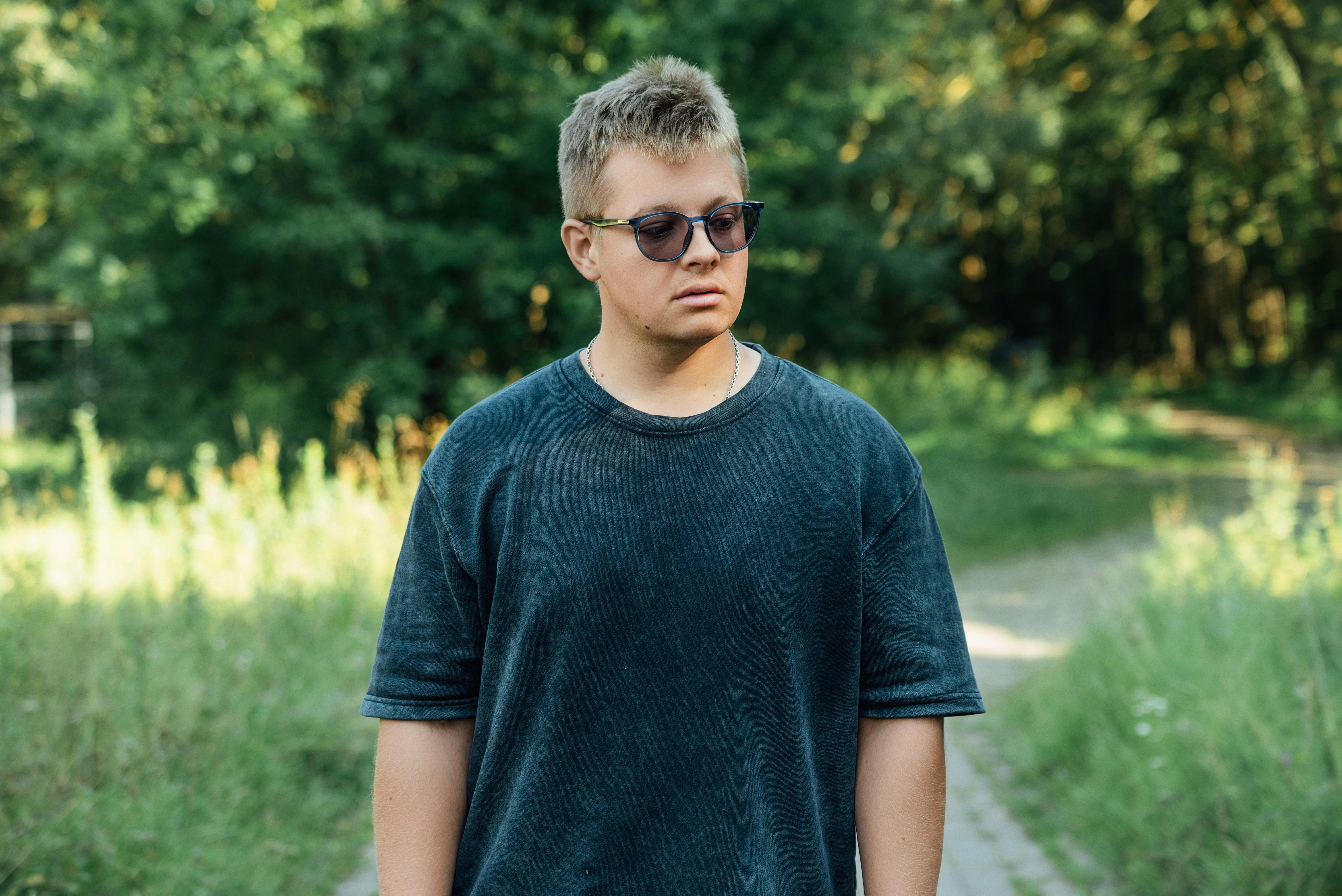 a young man in sunglasses standing in the woods