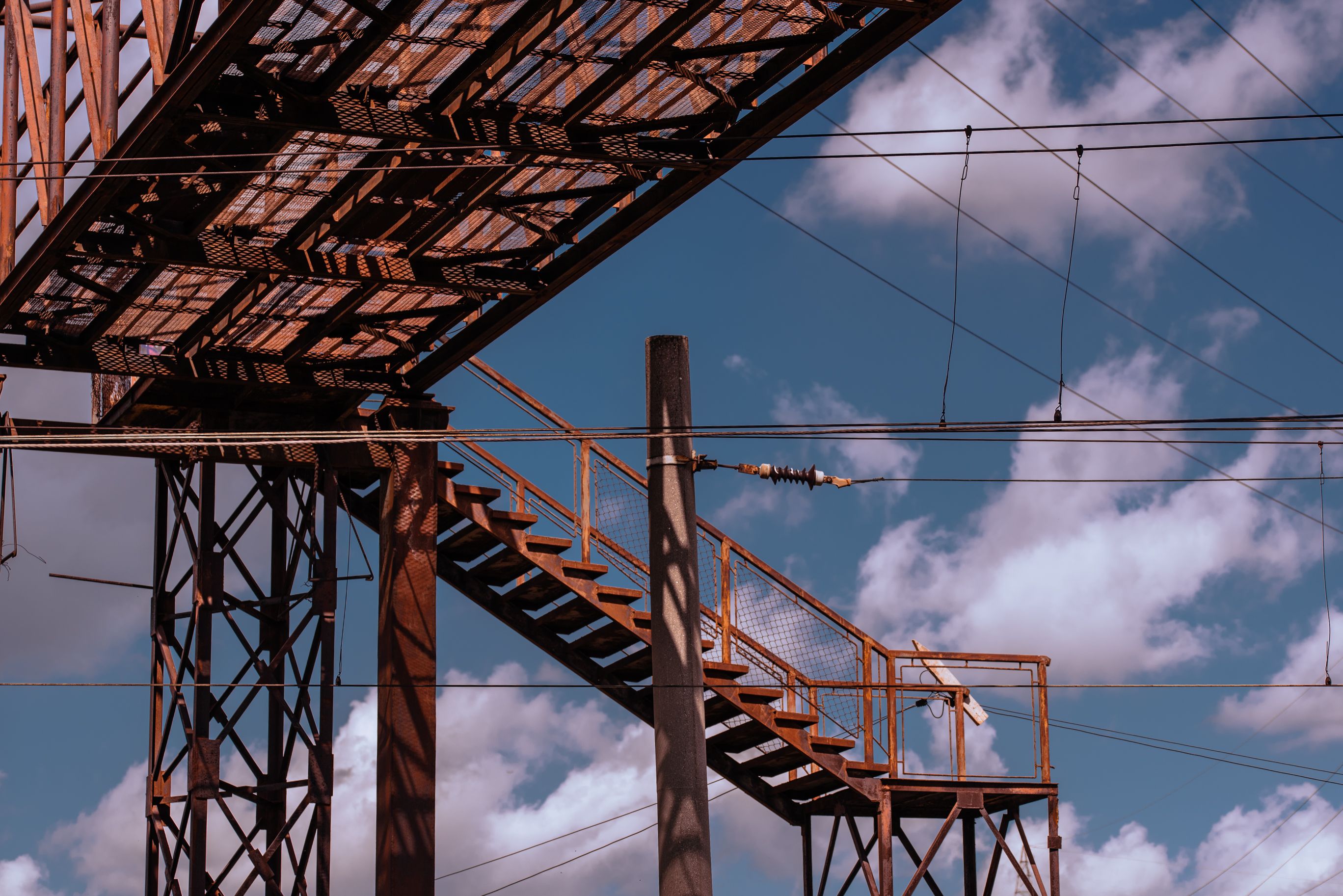 Estrutura de ferro de uma Passarela elevada sob um céu parcialmente nublado, destacando elementos de engenharia e construção.