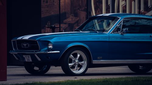 Free A vintage blue Ford Mustang GT with white stripes parked outdoors, showcasing its chrome details. Stock Photo