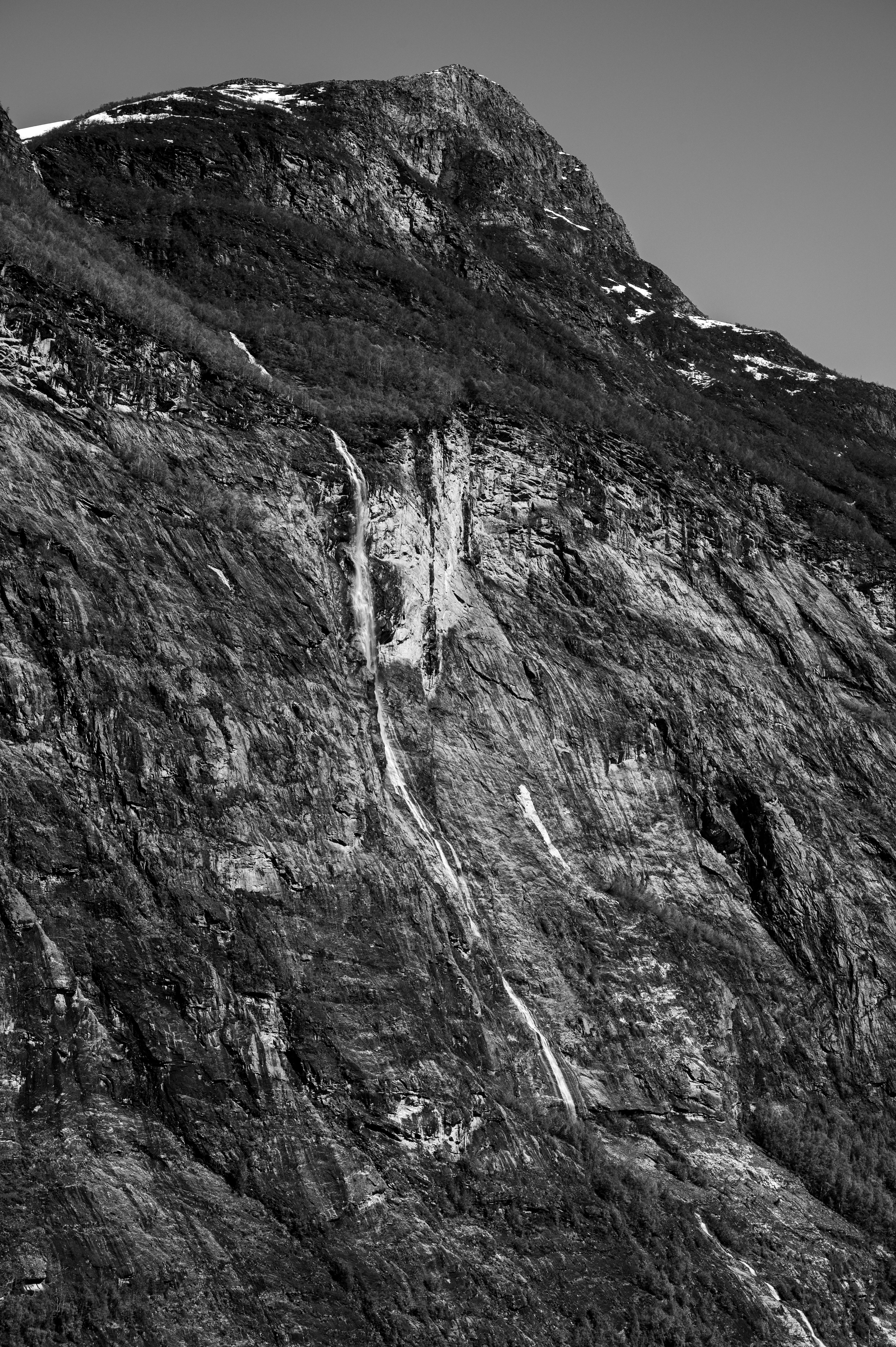 Stunning black and white photo of Geiranger Fjord's rocky landscape and waterfall.