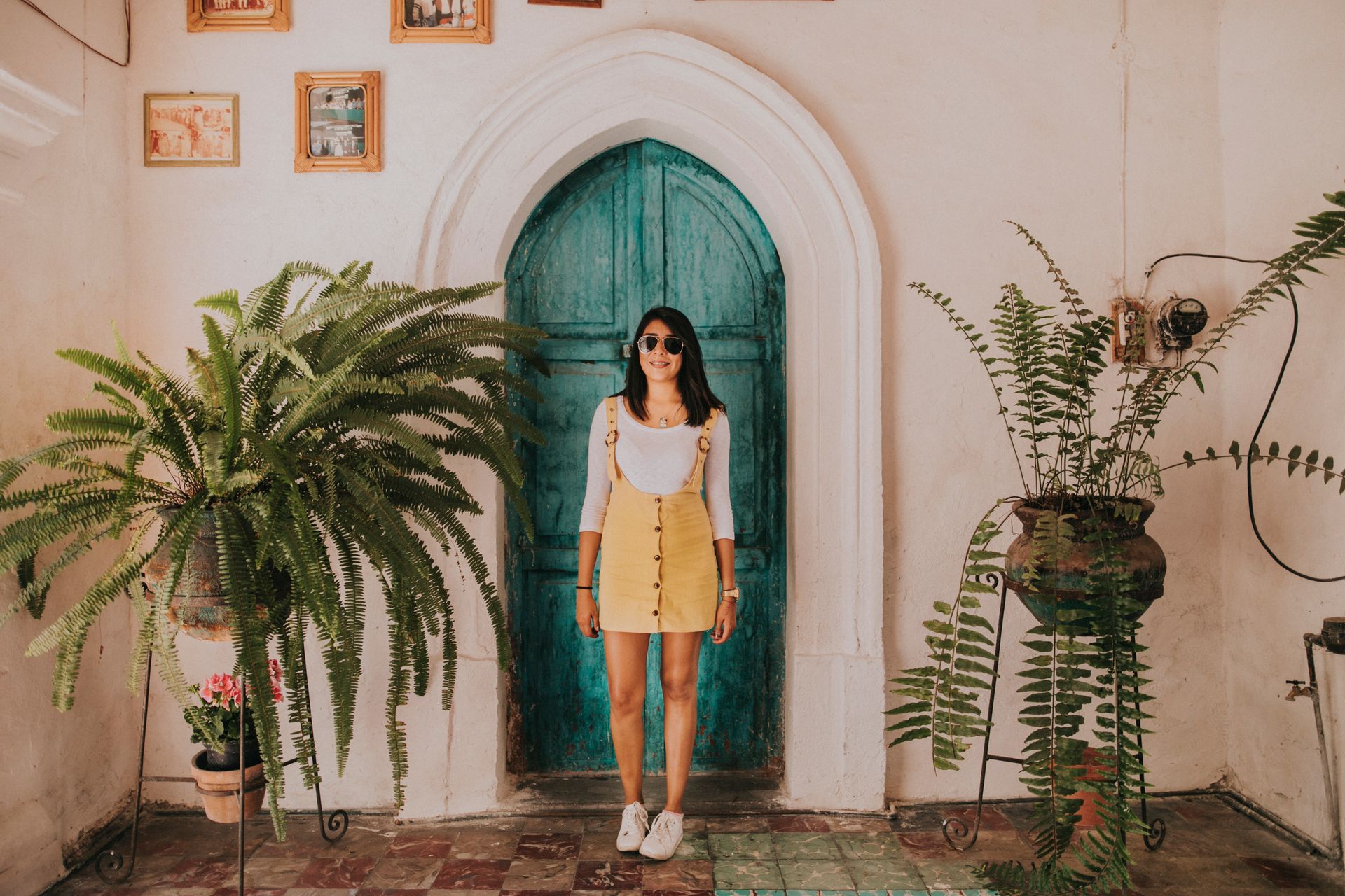 Woman Wearing Yellow Dungaree Skirt Standing in Front of Green Wooden Door