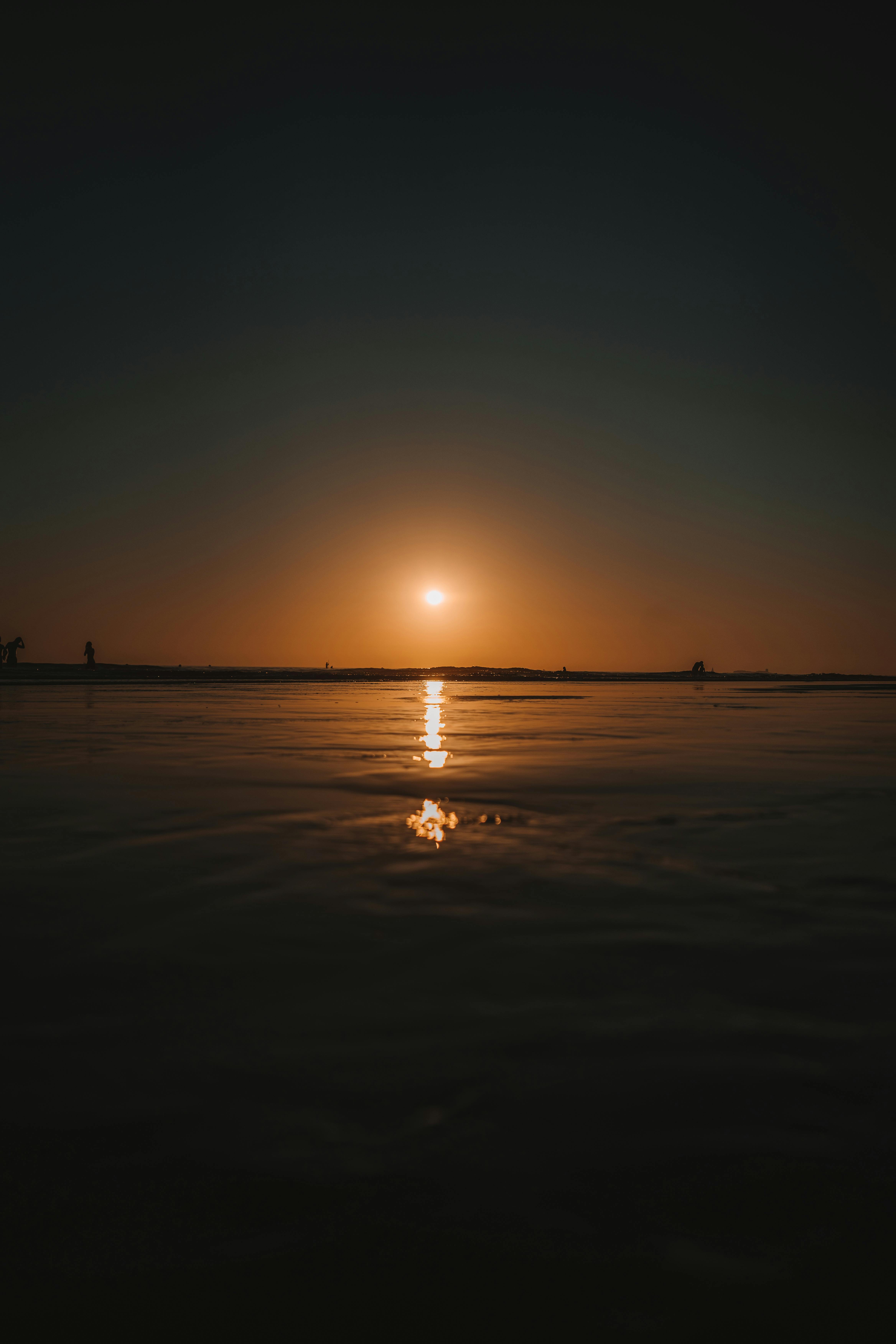 A tranquil sunset over a peaceful beach, with gentle waves and a warm orange glow.
