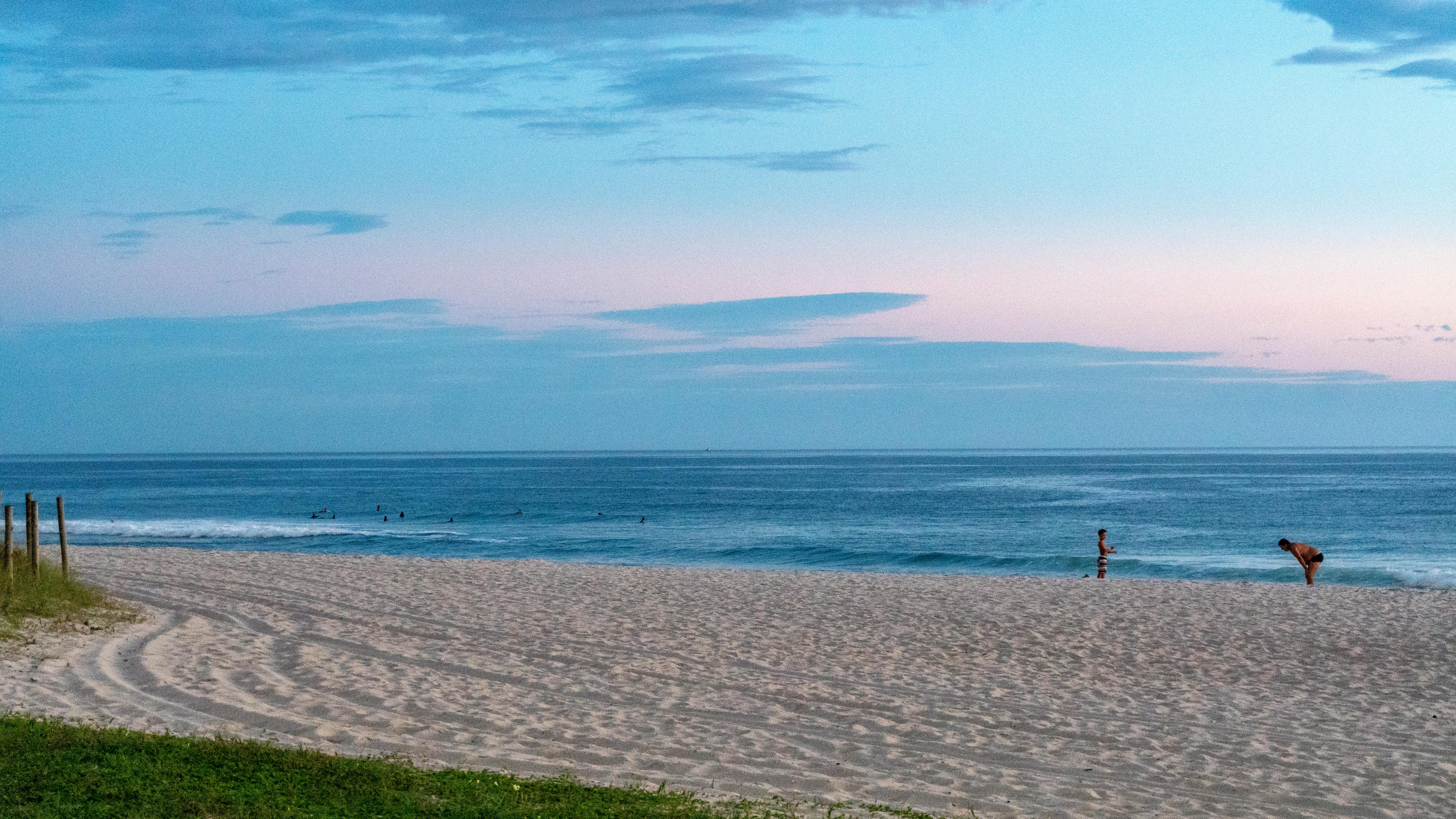 Beautiful sunset on Saquarema beach, Brazil, with a pink sky and calm ocean waves.