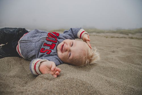 砂の上に横たわっている少年の写真