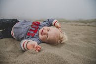 在雾蒙蒙的海滩上，可爱的孩子躺在沙滩上微笑着，享受着有趣的一天