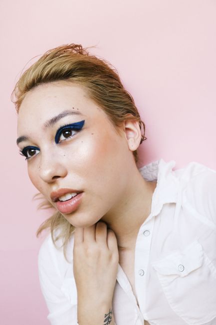 Vibrant portrait of a woman with striking blue eyeliner and a chic expression.