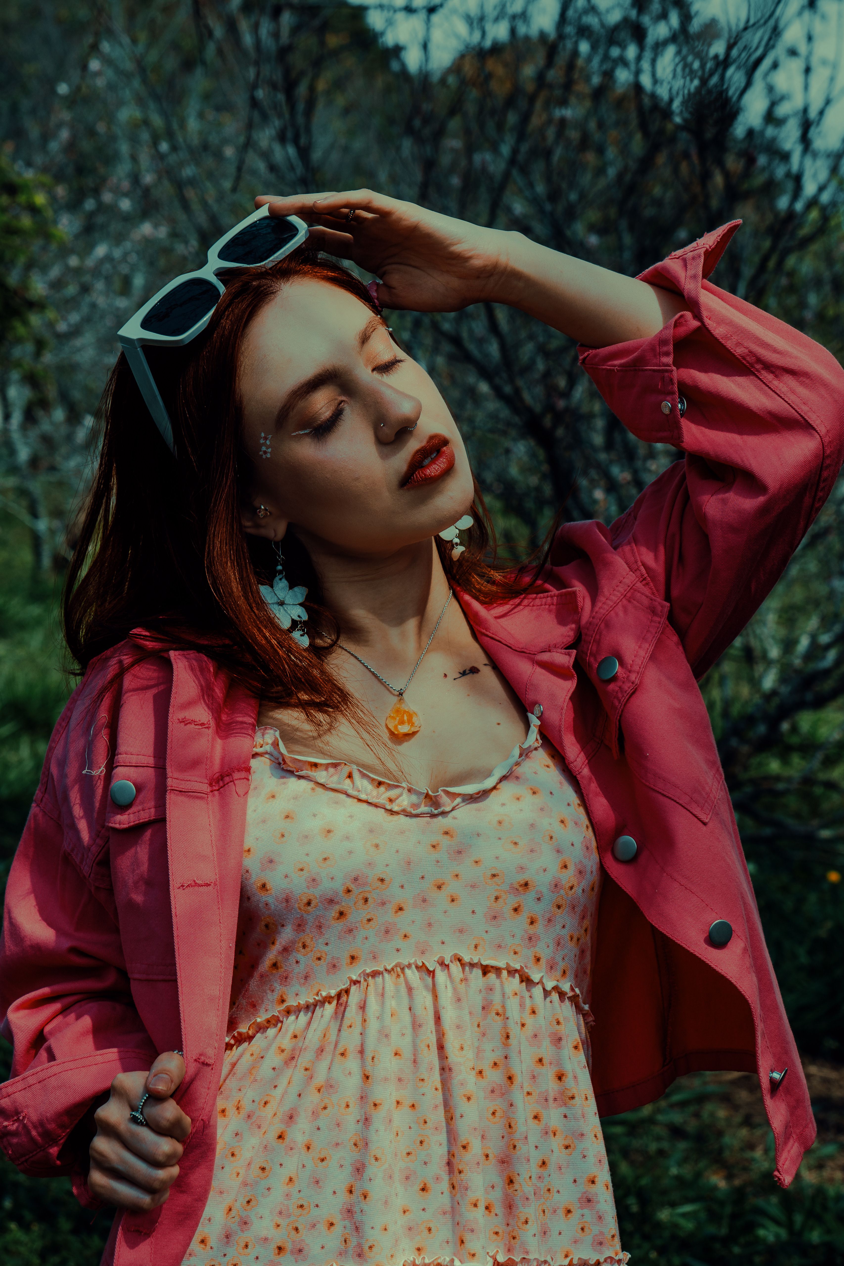 Portrait of a stylish young woman in sunglasses enjoying a sunny day outdoors with a relaxed pose.
