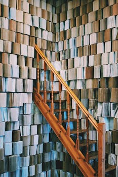 Wooden staircase with a unique abstract book wall background indoors.