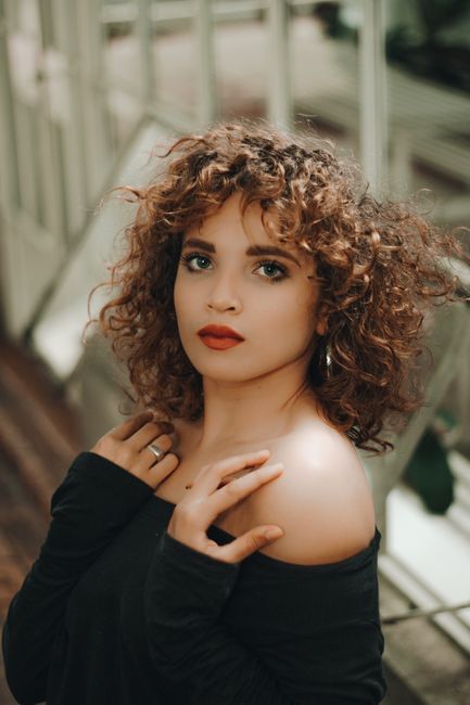 Stunning portrait of a woman with curly hair and bold makeup, evoking elegance in a fashionable setting.