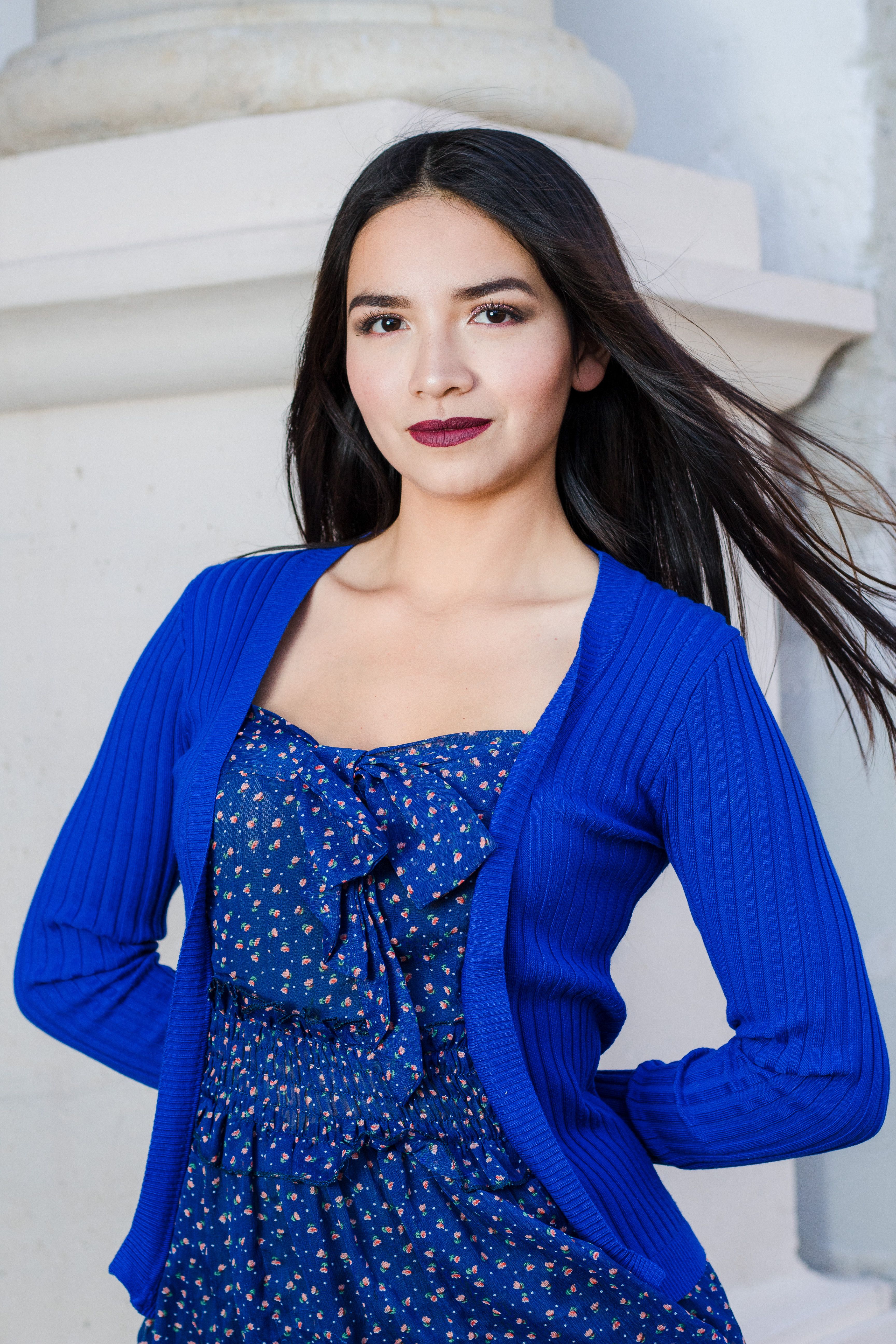 Elegant portrait of a young woman in a blue dress with a floral pattern.