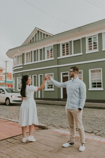 Happy couple dancing in front of a vintage building on a sunny day.