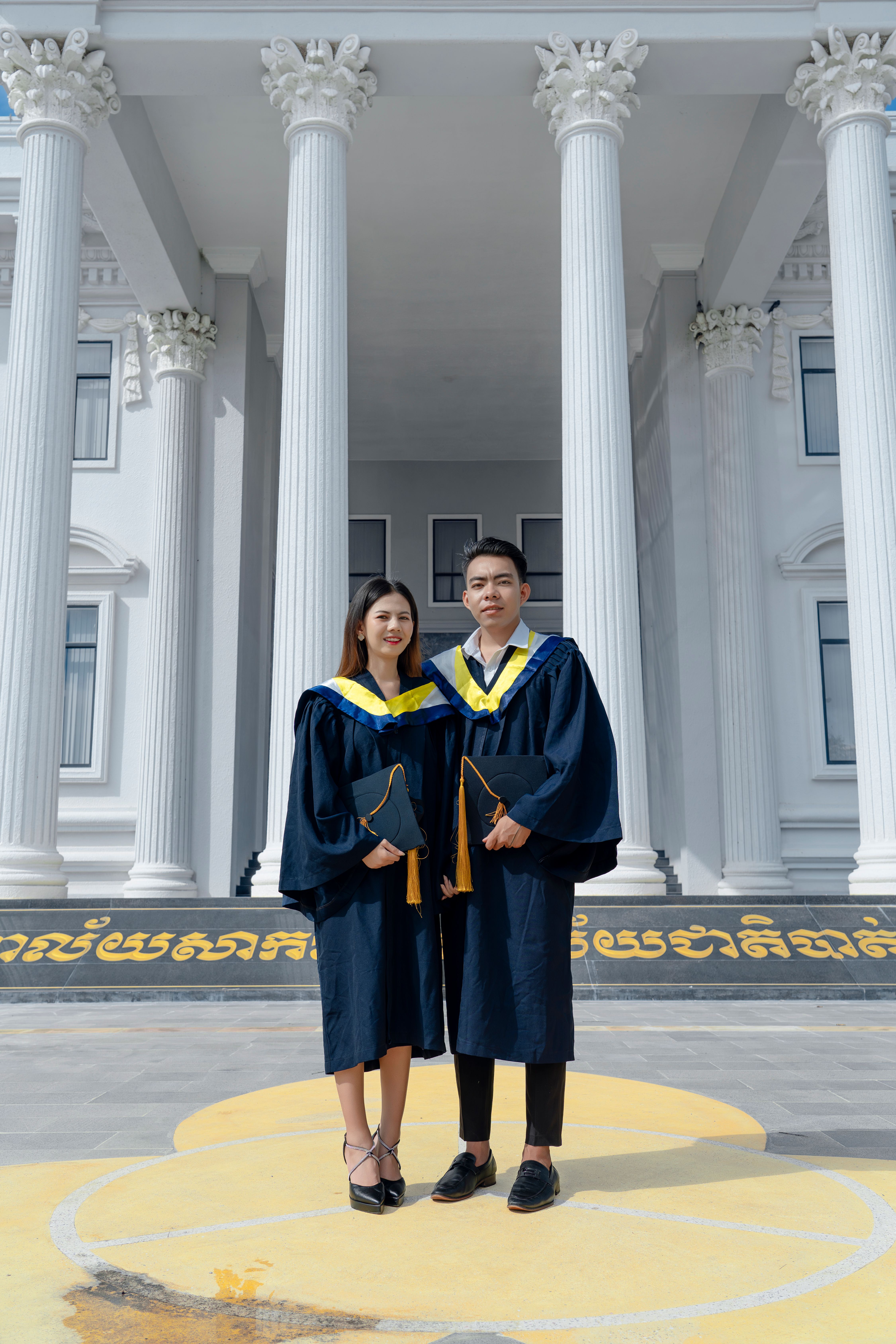 Two graduates posing for a photo in front of a building · Free Stock Photo