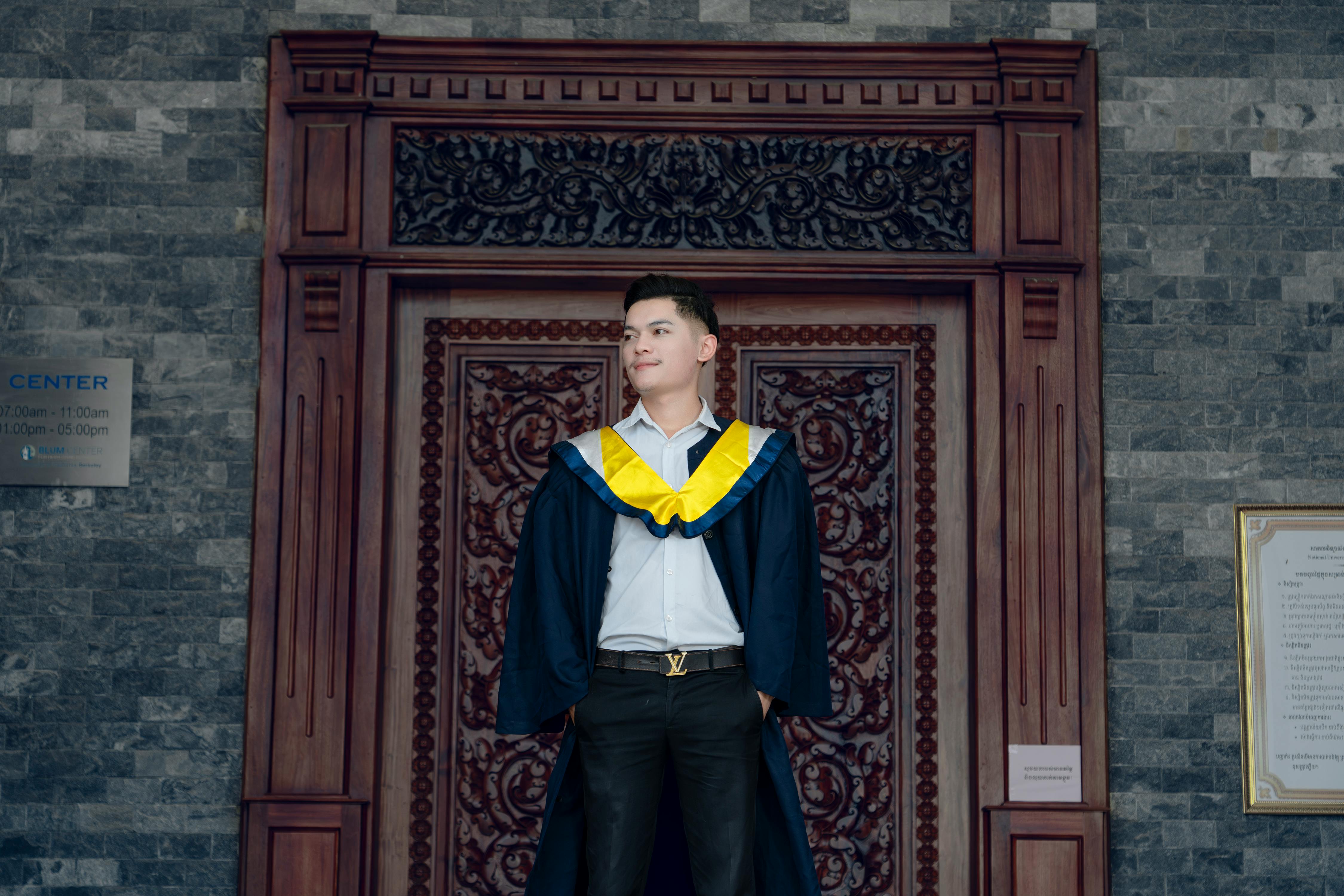 a man in a graduation gown standing in front of a door