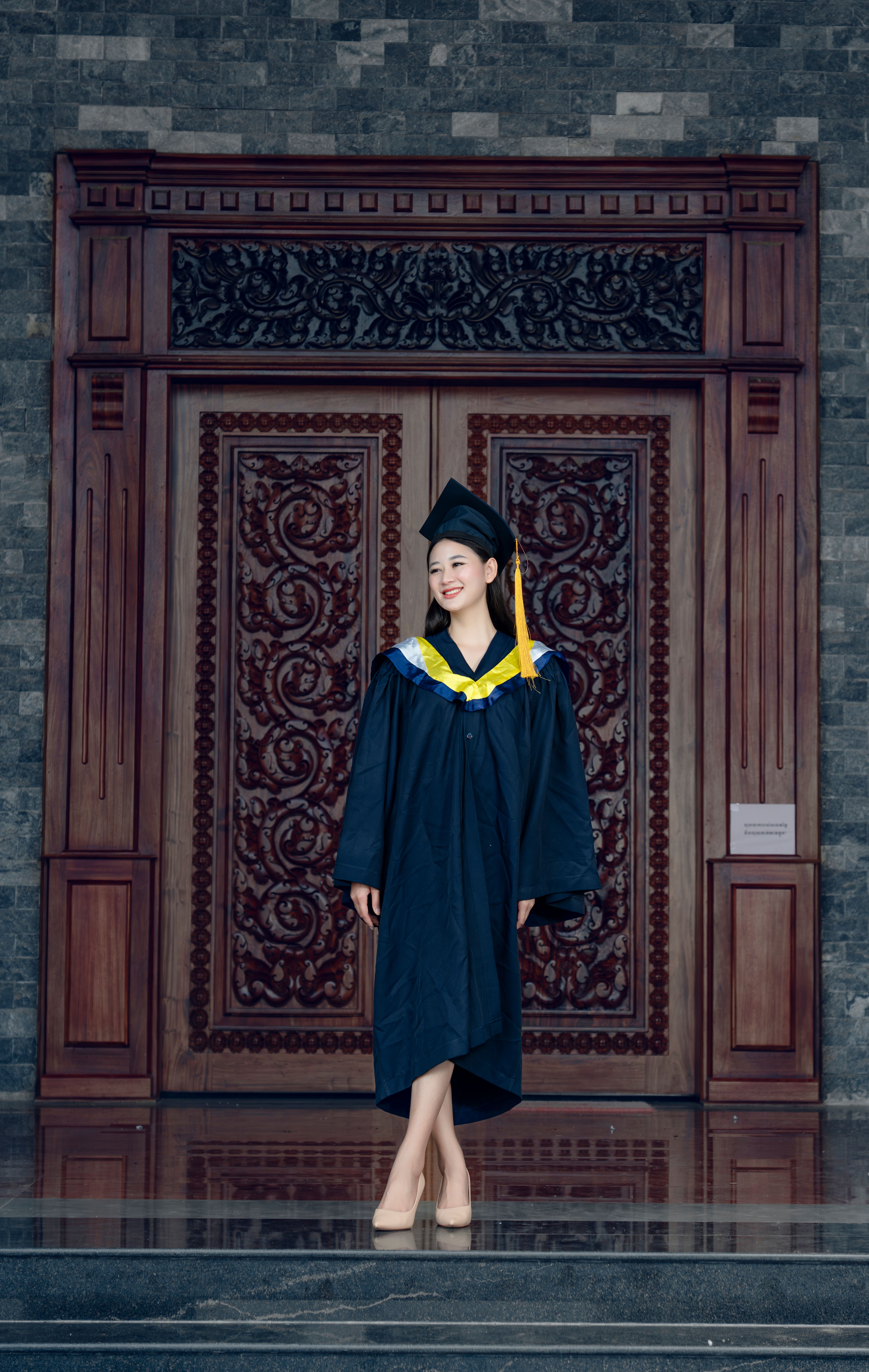 A woman in a graduation gown standing in front of a door · Free Stock Photo