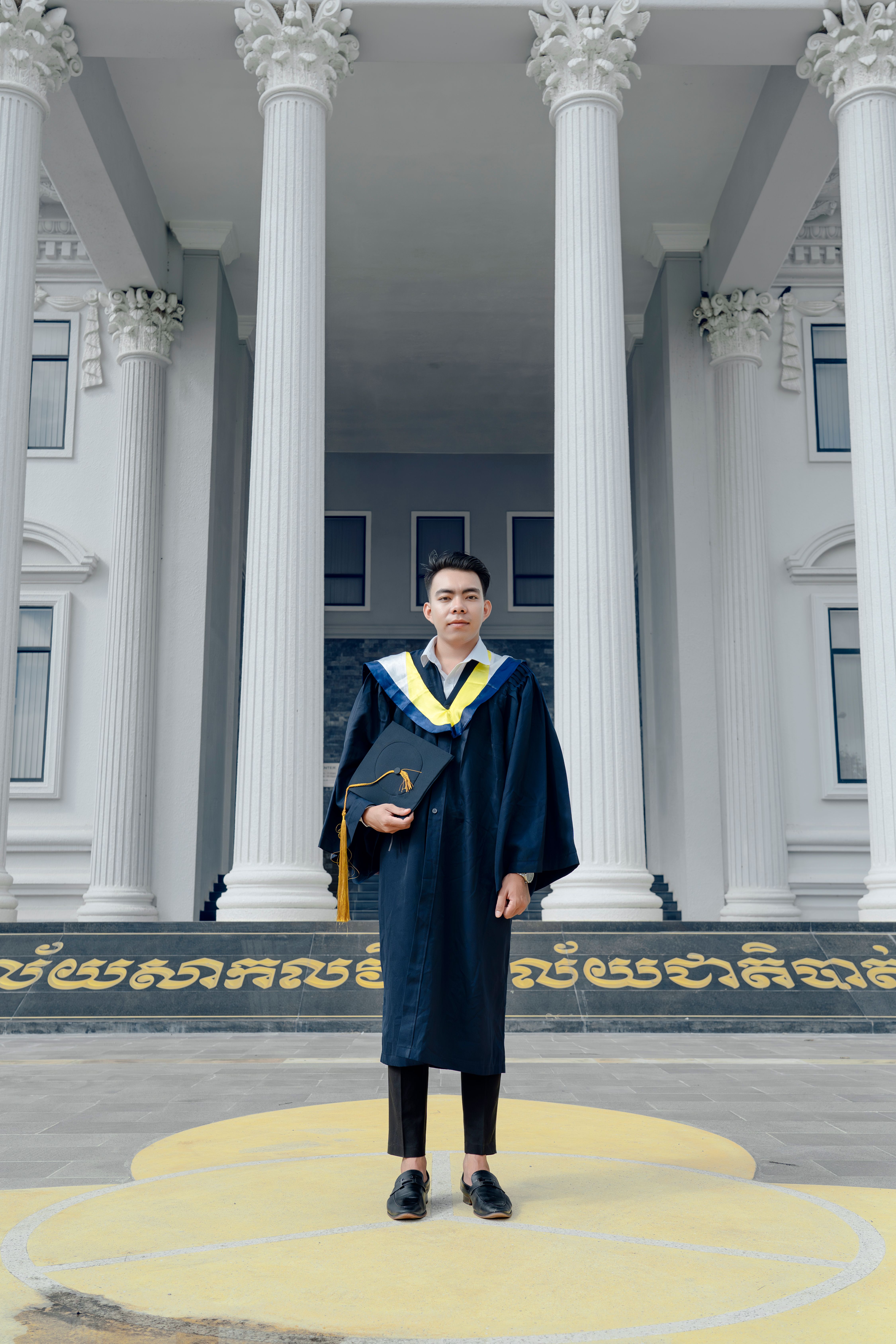 A man in a graduation gown standing in front of a building · Free Stock ...